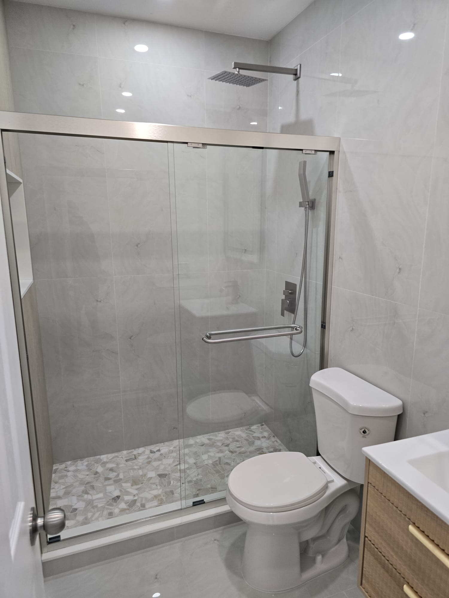 Baño con ducha de vidrio y piso de mosaico de mármol