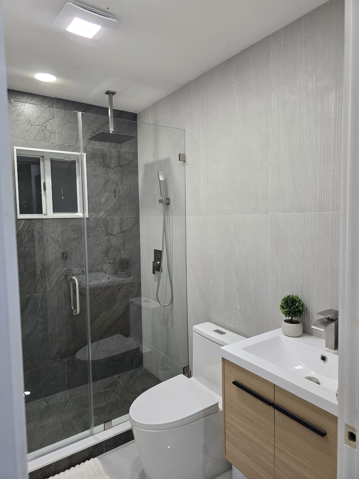 Baño con ducha en mármol gris y mueble de madera