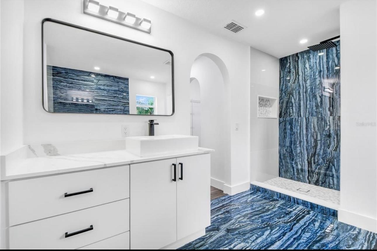 Baño moderno con pared de mármol azul y mueble blanco